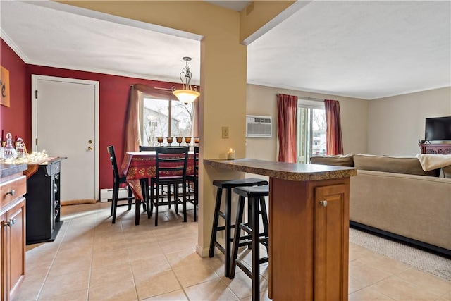 kitchen with light tile patterned floors, baseboard heating, a kitchen breakfast bar, and crown molding