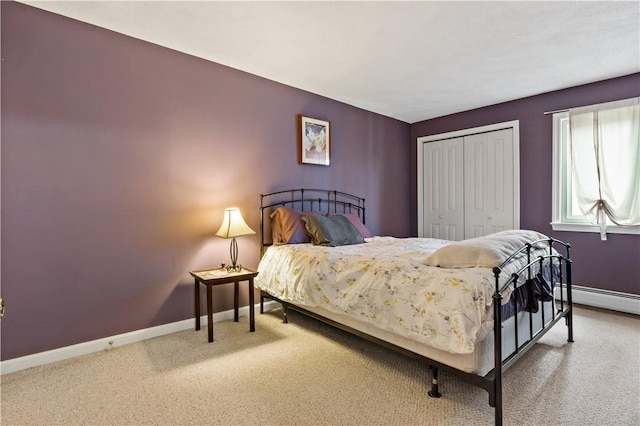 bedroom with a baseboard heating unit, carpet floors, baseboards, and a closet