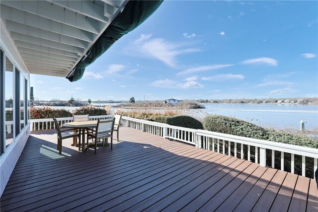 deck with outdoor dining area and a water view