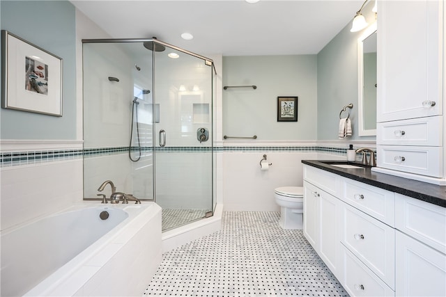 bathroom with toilet, a stall shower, tile walls, a bath, and vanity