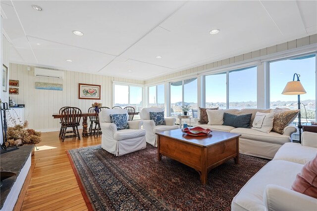 living area featuring recessed lighting, light wood-type flooring, a healthy amount of sunlight, and a wall unit AC