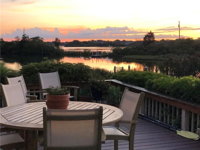 deck with outdoor dining space and a water view