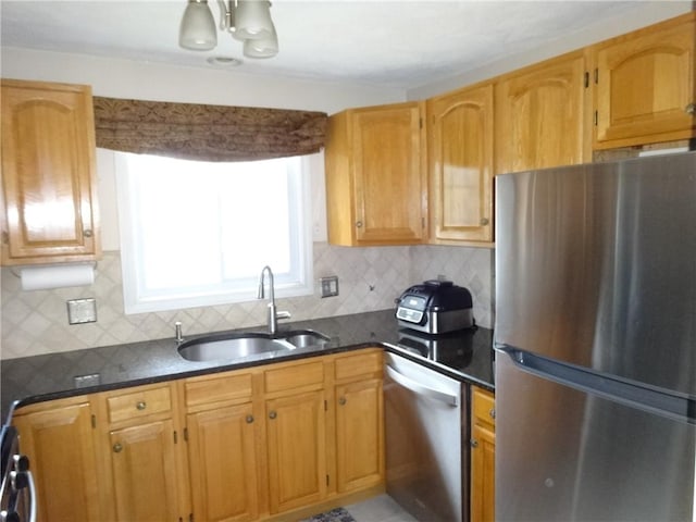 kitchen with dark stone countertops, tasteful backsplash, appliances with stainless steel finishes, and a sink