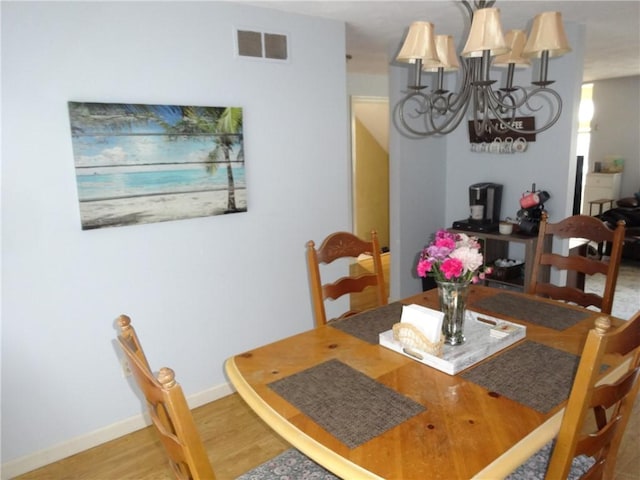 dining area with a chandelier, visible vents, baseboards, and wood finished floors