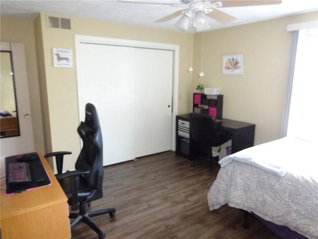 bedroom featuring dark wood-style floors, visible vents, a ceiling fan, and a closet