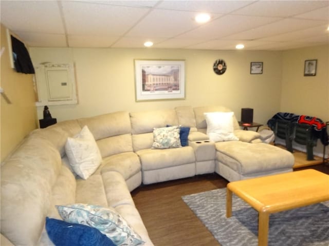 living room featuring electric panel, a drop ceiling, recessed lighting, and wood finished floors