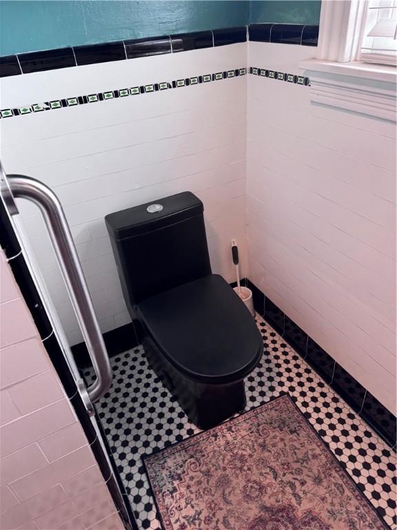 interior space with tile patterned flooring, tile walls, and toilet