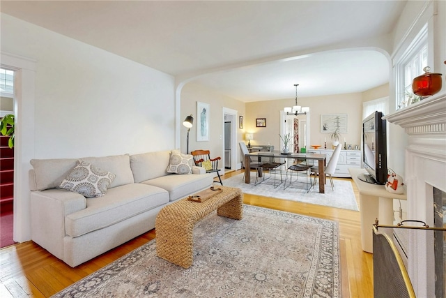 living room featuring plenty of natural light, light wood-type flooring, and an inviting chandelier