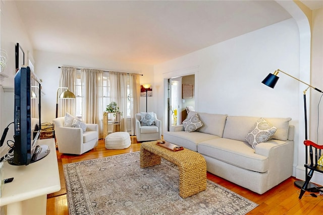 living room with arched walkways and light wood-style flooring