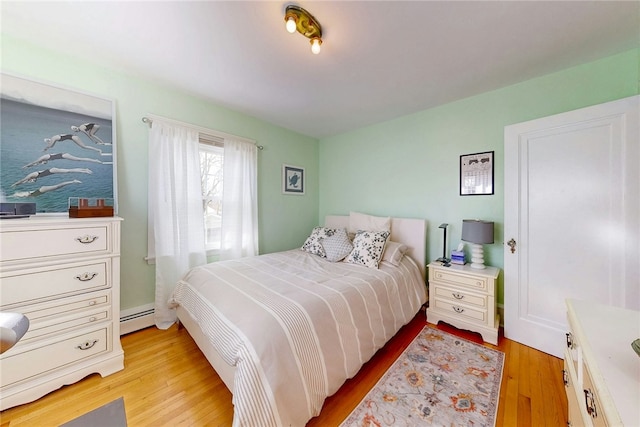 bedroom with light wood-style floors and a baseboard radiator