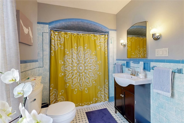 full bathroom featuring wainscoting, tile walls, and toilet