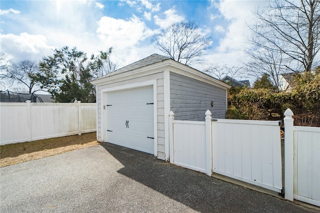 detached garage with aphalt driveway and fence