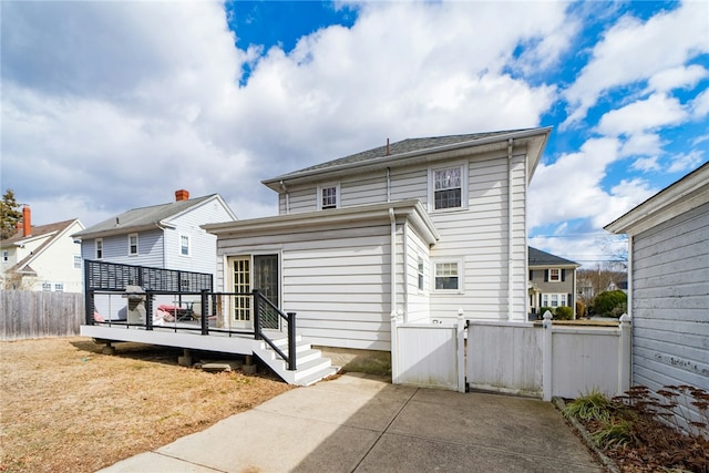 back of property with a patio area, a wooden deck, a gate, and fence