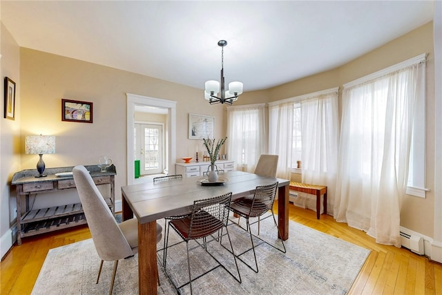 dining room with a baseboard heating unit, light wood-style floors, baseboards, and a chandelier