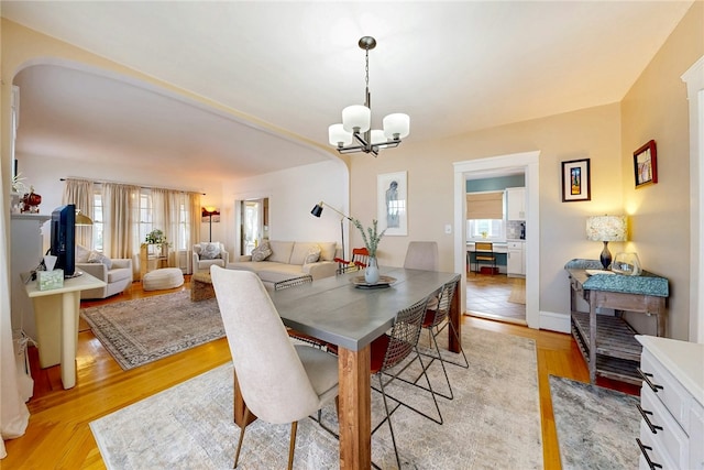 dining area with a chandelier, plenty of natural light, and light wood-style flooring