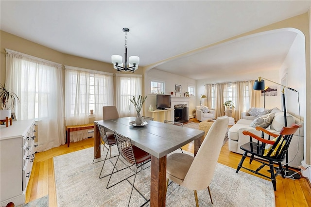 dining area with plenty of natural light, a fireplace with raised hearth, and light wood-style floors