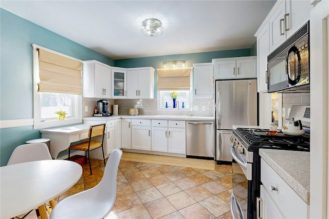 kitchen with decorative backsplash, light countertops, white cabinets, and stainless steel appliances