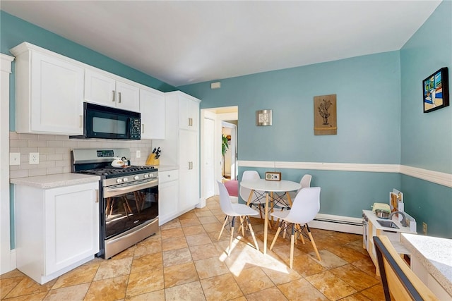 kitchen featuring decorative backsplash, light countertops, black microwave, stainless steel gas range oven, and white cabinetry