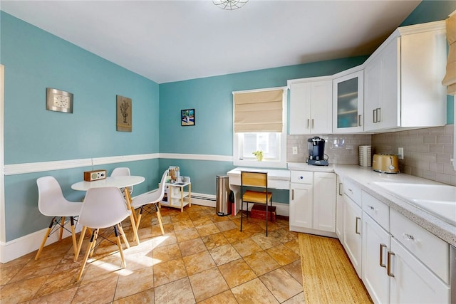 kitchen with decorative backsplash, glass insert cabinets, white cabinets, and light countertops