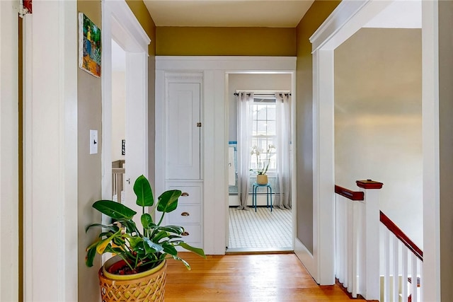 corridor with an upstairs landing and wood finished floors