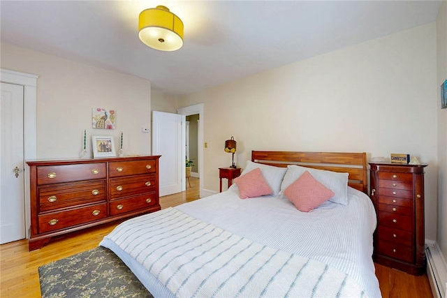 bedroom featuring light wood-style flooring and a baseboard heating unit