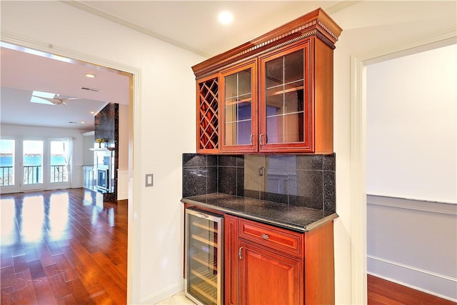 bar with a dry bar, wine cooler, wood finished floors, and backsplash