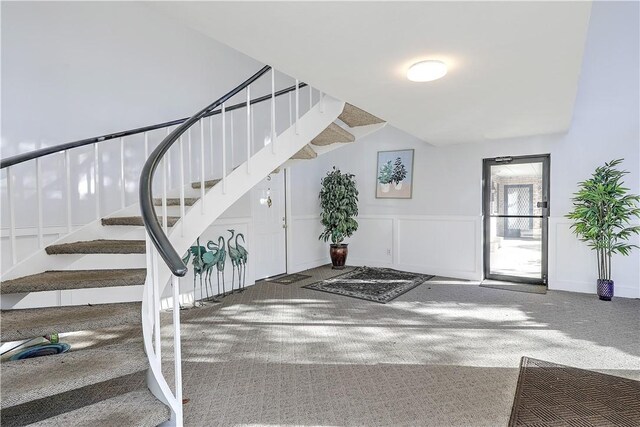 foyer featuring stairway, carpet flooring, a decorative wall, and a wainscoted wall