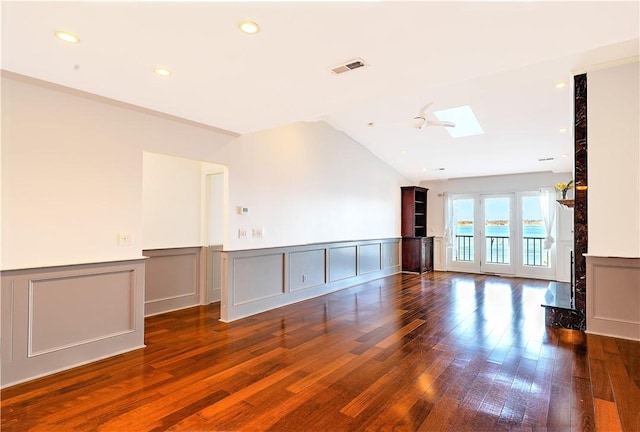 unfurnished living room with visible vents, lofted ceiling with skylight, wainscoting, recessed lighting, and hardwood / wood-style flooring