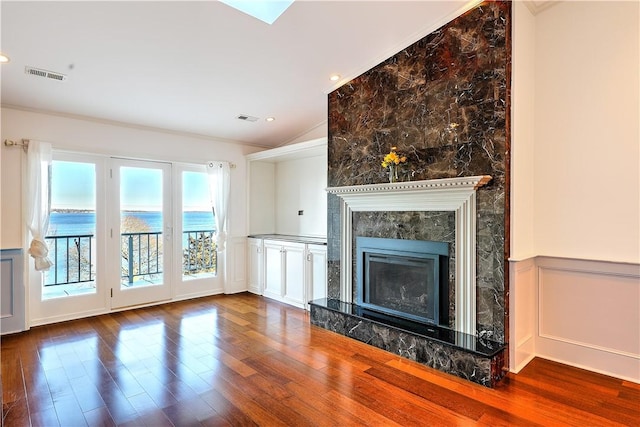 unfurnished living room featuring a high end fireplace, visible vents, wainscoting, and wood finished floors