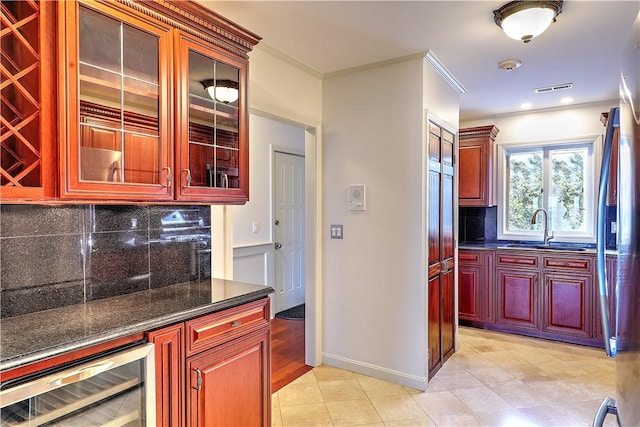 kitchen with beverage cooler, ornamental molding, a sink, backsplash, and reddish brown cabinets