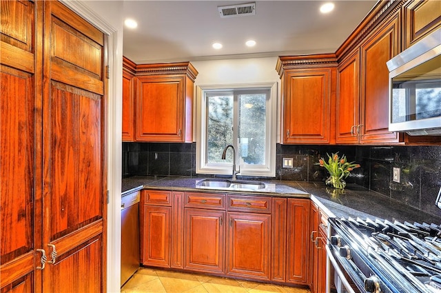 kitchen featuring visible vents, a sink, dark stone countertops, stainless steel appliances, and decorative backsplash