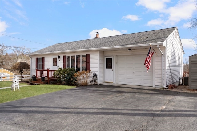 single story home featuring aphalt driveway, central AC, an attached garage, and a shingled roof