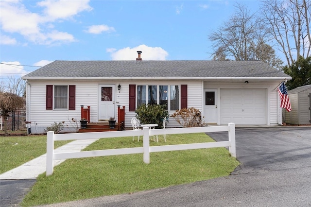 single story home featuring a shingled roof, a front lawn, a fenced front yard, driveway, and an attached garage