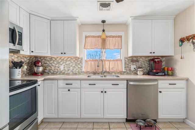 kitchen featuring tasteful backsplash, visible vents, white cabinets, stainless steel appliances, and a sink