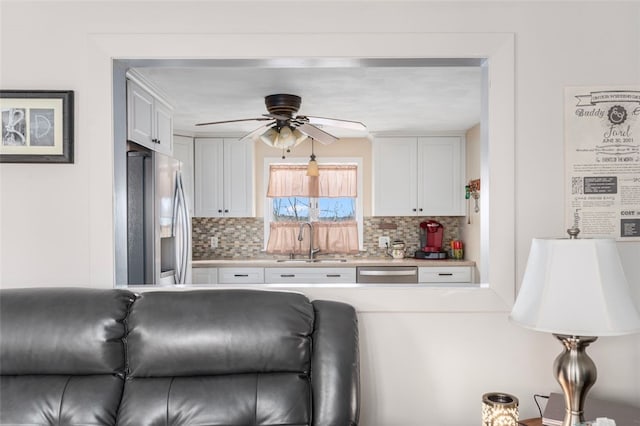 kitchen featuring a sink, appliances with stainless steel finishes, white cabinets, and light countertops