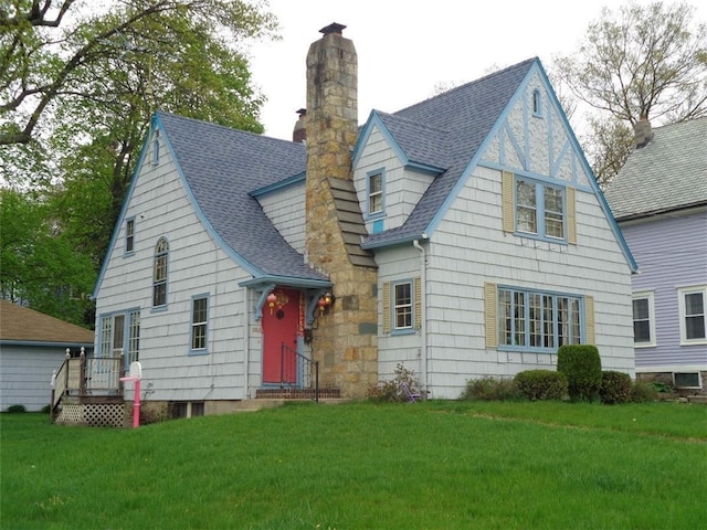 view of front of house featuring a chimney, a front yard, and a shingled roof