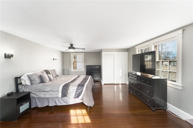 bedroom with radiator, baseboards, dark wood-type flooring, and a ceiling fan