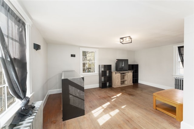 living room featuring radiator heating unit, baseboards, and wood finished floors