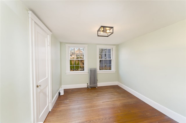 empty room featuring radiator, light wood-style floors, and baseboards