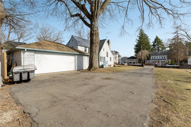 view of property exterior featuring a garage, a residential view, and an outdoor structure