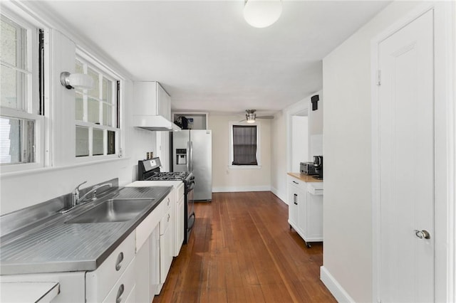 kitchen with stainless steel refrigerator with ice dispenser, a sink, stainless steel counters, white cabinets, and gas range