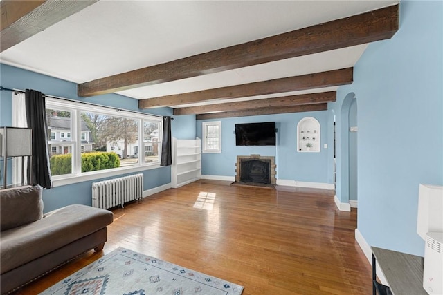 living room with baseboards, arched walkways, wood finished floors, and radiator heating unit