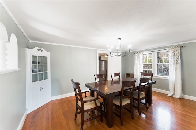 dining area featuring ornamental molding, wood finished floors, baseboards, and a chandelier