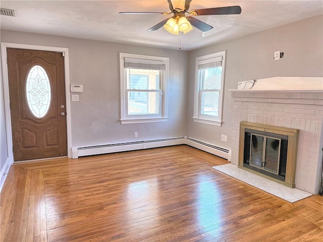 entrance foyer with ceiling fan, visible vents, wood finished floors, and a fireplace