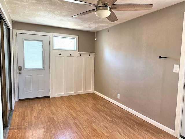 entryway with ceiling fan, a textured ceiling, light wood-type flooring, and baseboards