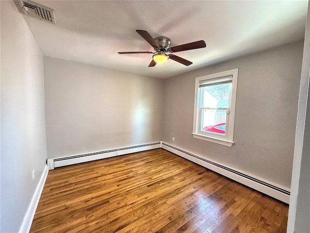 spare room with visible vents, wood-type flooring, a ceiling fan, and a baseboard radiator