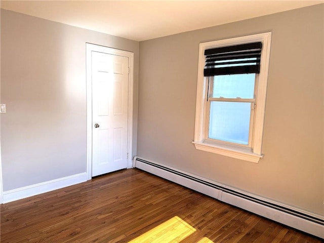 unfurnished room with dark wood-style floors, baseboards, and a baseboard radiator