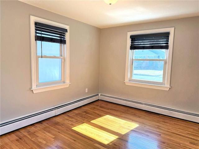 spare room with wood finished floors and a baseboard radiator