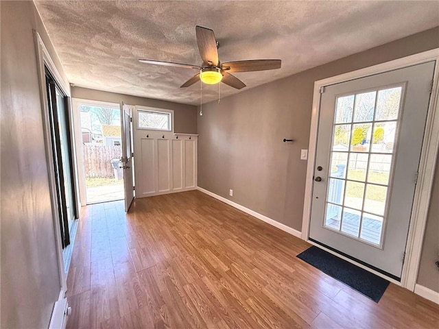 entryway with ceiling fan, a textured ceiling, baseboards, and wood finished floors