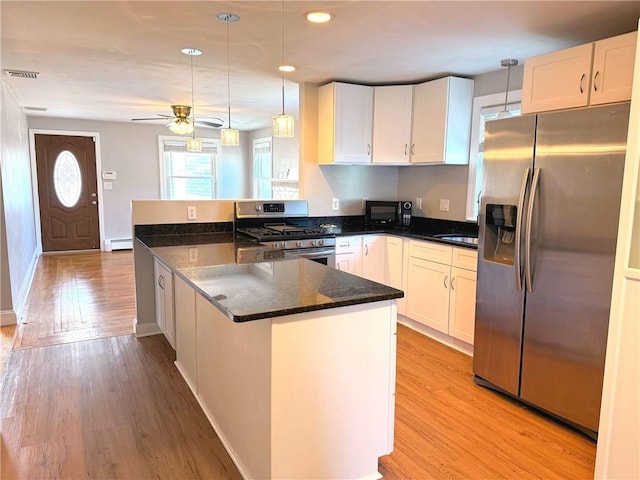 kitchen with baseboard heating, appliances with stainless steel finishes, a peninsula, and white cabinetry